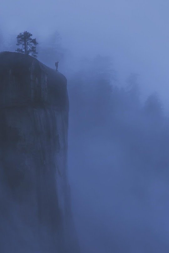 man standing of cliff in fog