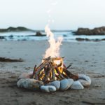 campfire surrounded by rocks on beach