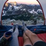 man and woman enjoying mountain view from tent