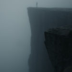 man standing on foggy cliff