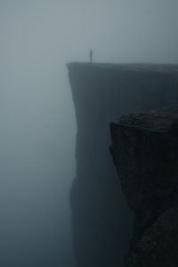 man standing on foggy cliff