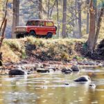 red ford bronco by a stream