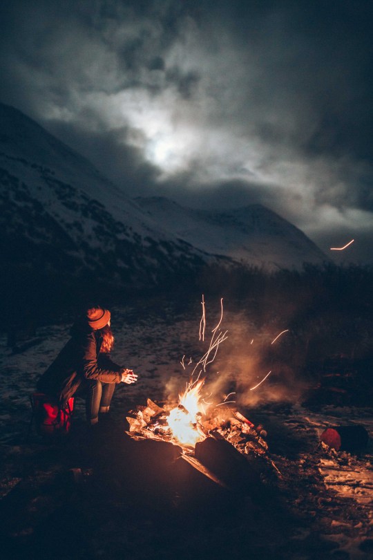 woman near campfire with dramtic night sky in background