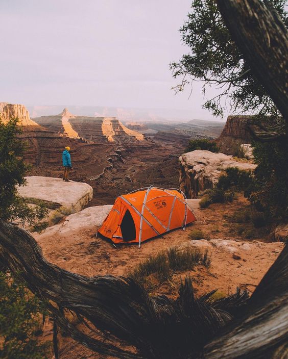 man standing near tent on edge of canyon