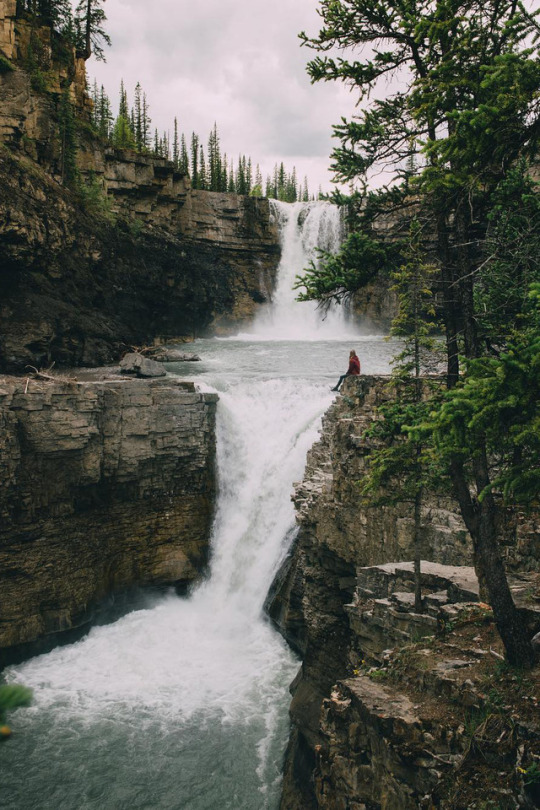 woman sitting near edge of waterfall