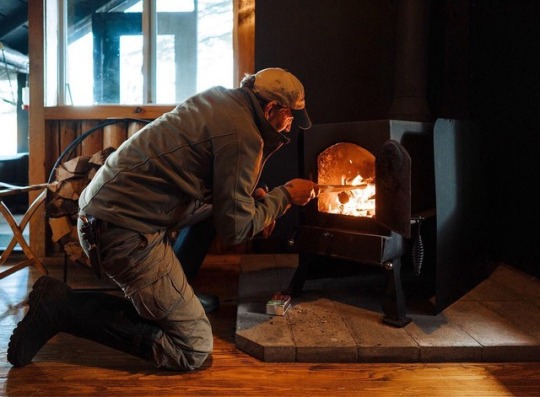 man tending to fire in wood burning stove
