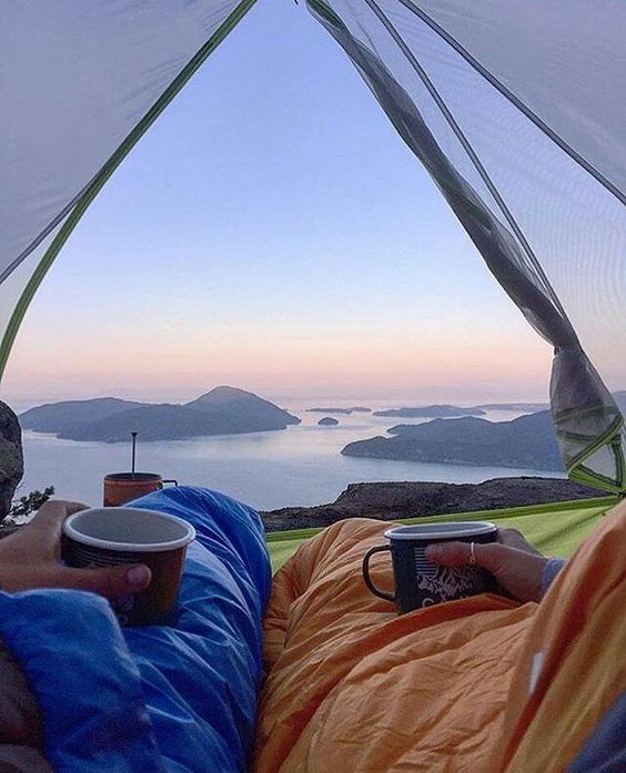 man and woman looking out of tent admiring view