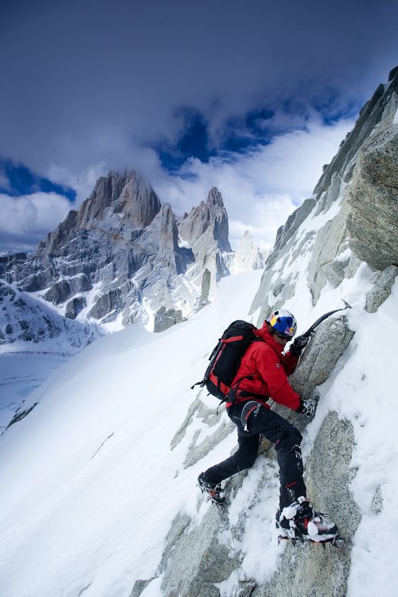 man climbing a snow-covered mountain