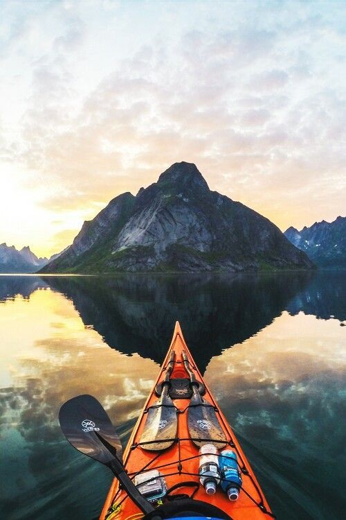 man paddling canoe in mountain lake