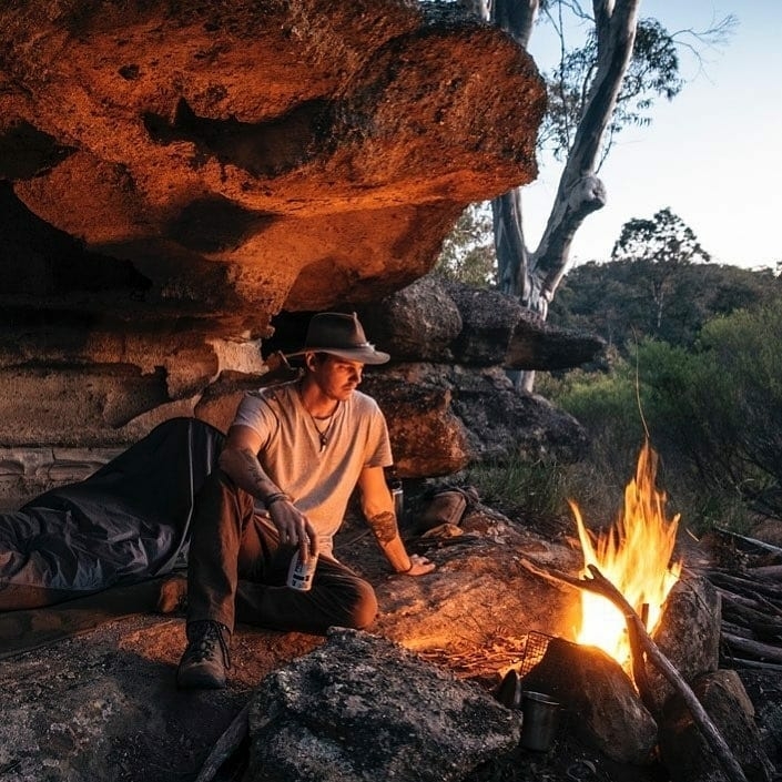man relaxing by campfire