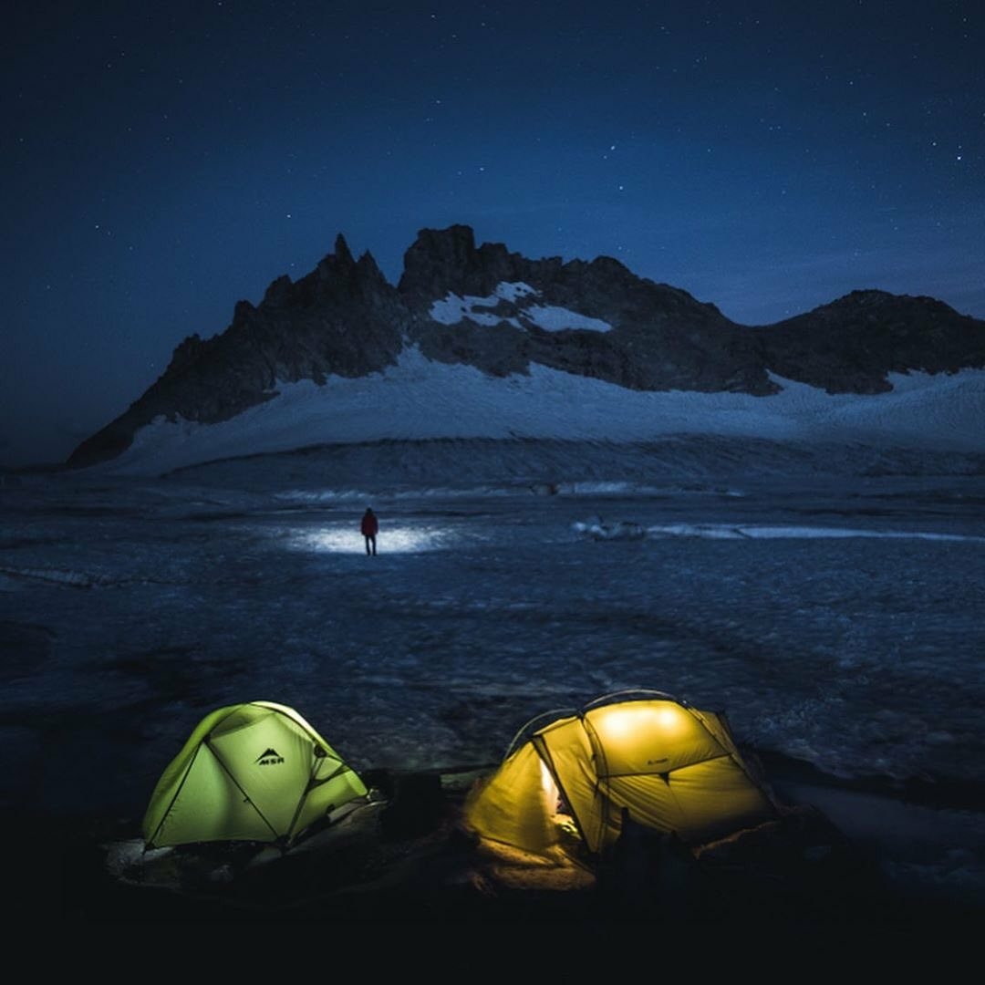 tents lit up near snow covered mountain