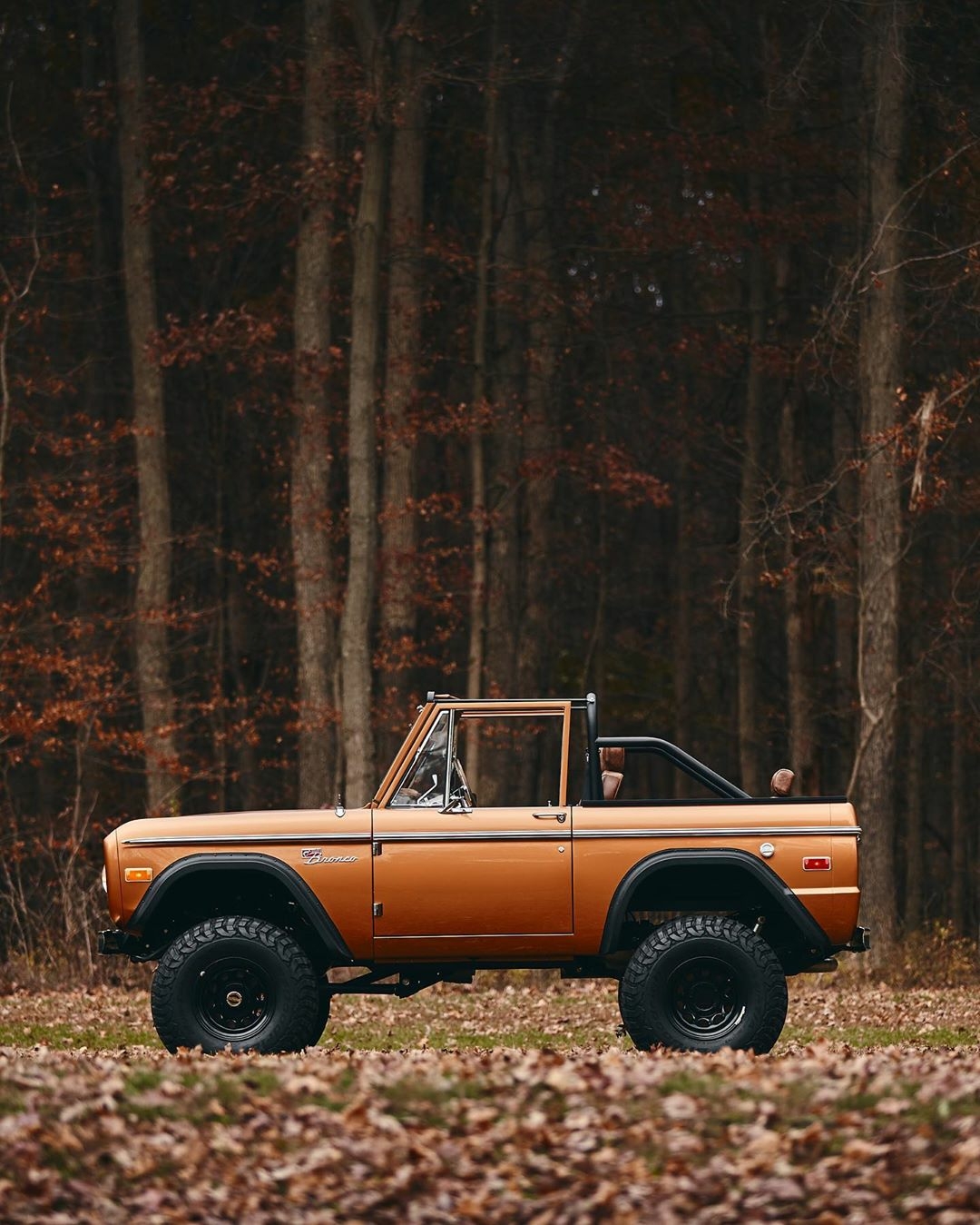 orange ford bronco in the woods