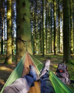 the manly life - man relaxing on hammock in forest