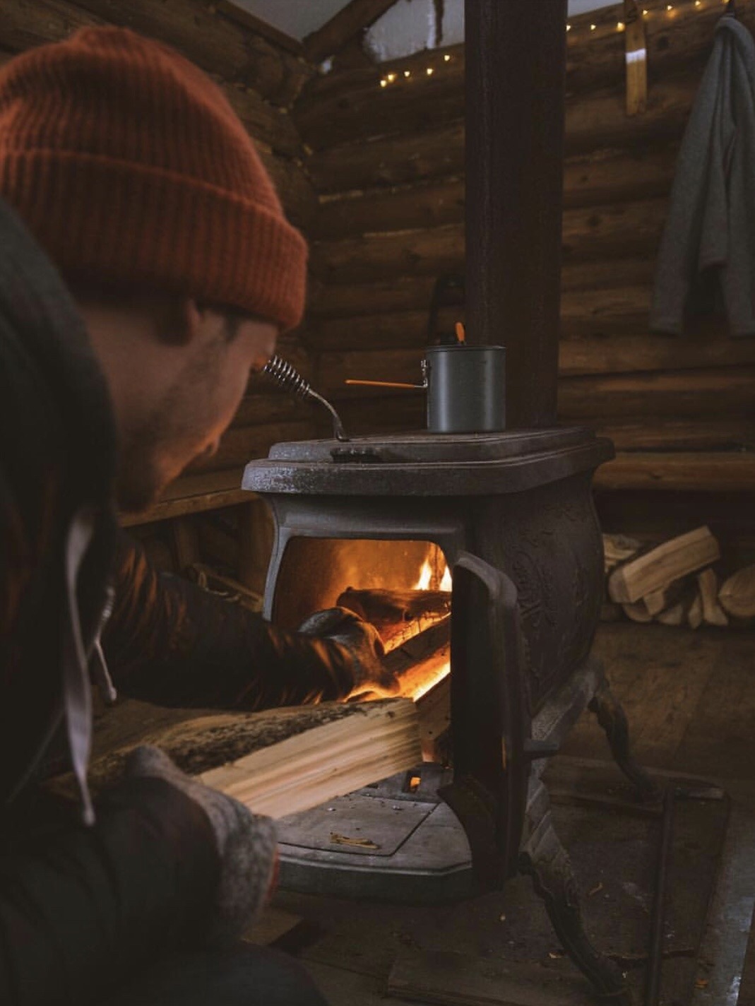 man adding firewood to stove