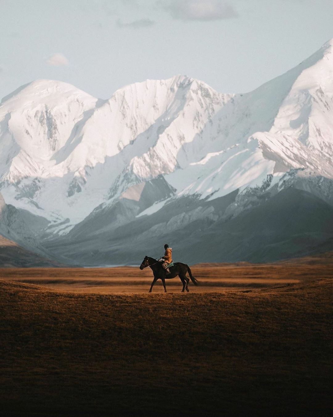 man riding horse with mountains in background