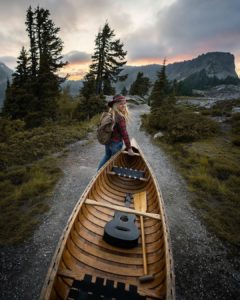 the manly life - woman helping carry a canoe in the pacific northwest