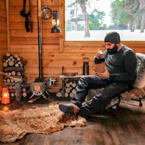 man reading and drinking coffee inside cabin