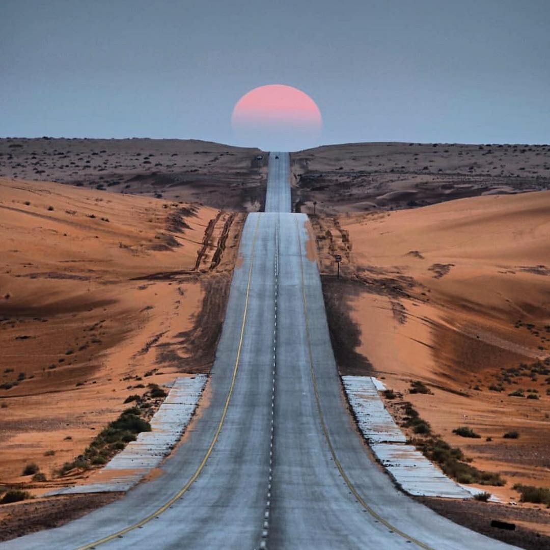 long road with sun setting ahead