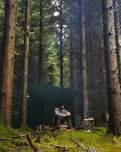 the manly life - man sitting under shelter in woods