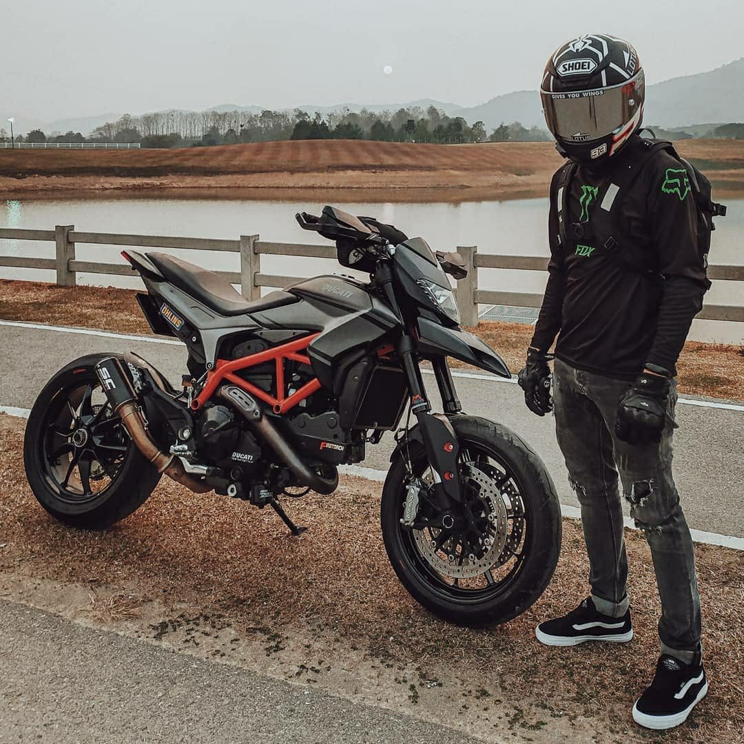 man standing next to ducati on side of road